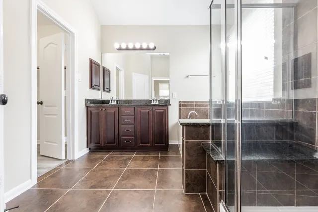 a bathroom with a granite countertop sink a toilet and shower