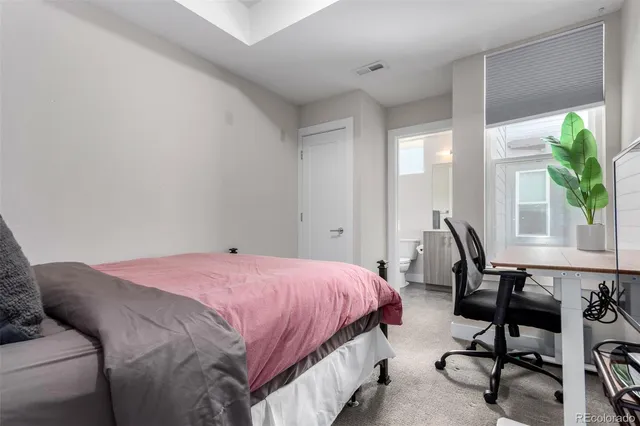 a bedroom with a bed a desk and chair with the potted plants