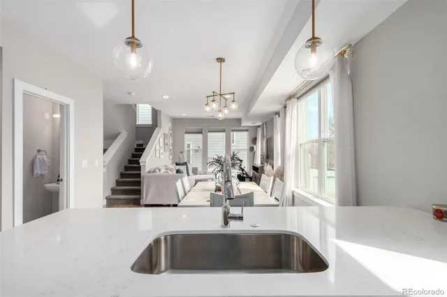 a kitchen with a sink a faucet a chandelier and couches