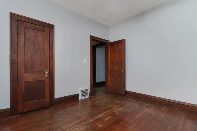 a view of an empty room with wooden floor and closet