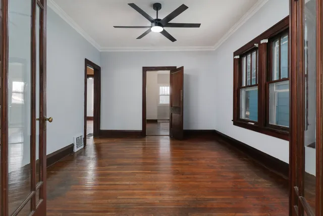 a view of an empty room with window and wooden floor