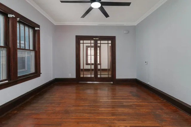 a view of an empty room with wooden floor and a window