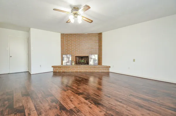 an empty room with wooden floor fireplace and window