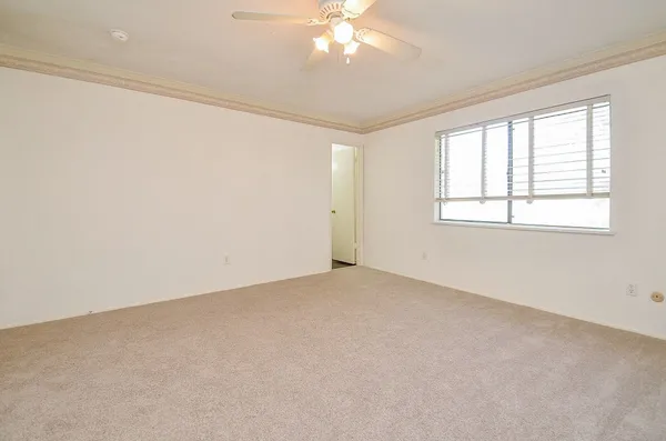 an empty room with windows and chandelier fan