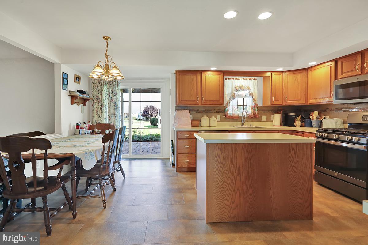 103 Eagles Lane Reading, PA 19608 - Photo 13 of 42 a kitchen with stainless steel appliances granite countertop a stove top oven a sink dishwasher a dining table and chairs with wooden floor
