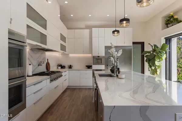 a kitchen with stainless steel appliances granite countertop a sink a counter top space a stove and cabinets