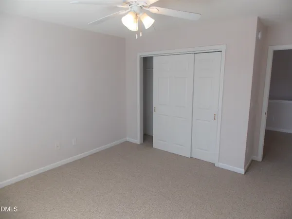 a view of an empty room and chandelier fan
