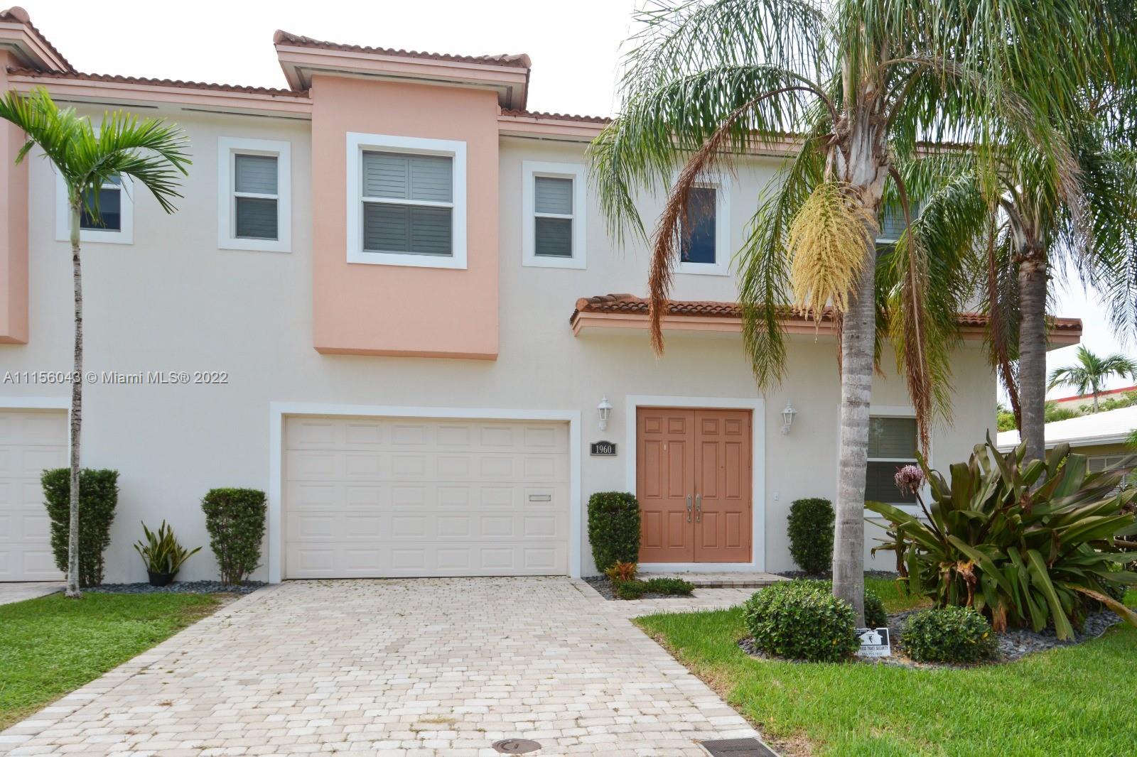 1960 Northeast 33rd Street Lighthouse Point, FL 33064 - Photo 2 of 24 a front view of a house with a garden