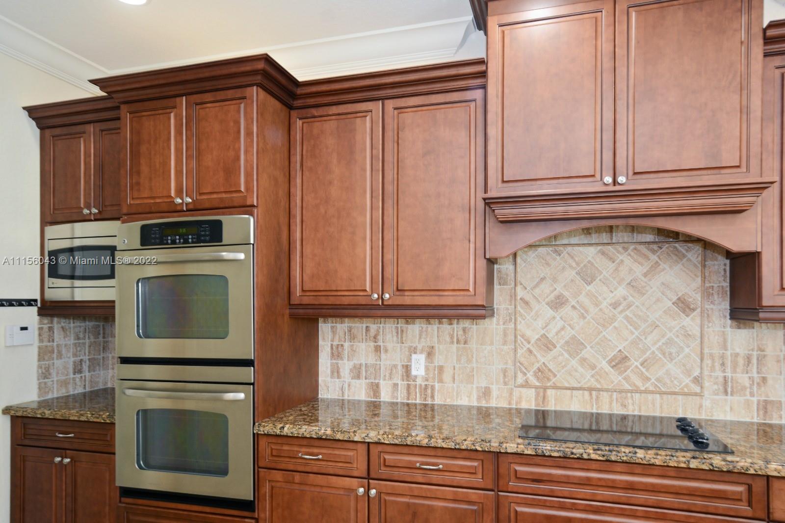 1960 Northeast 33rd Street Lighthouse Point, FL 33064 - Photo 7 of 24 a kitchen with granite countertop wooden cabinets and stainless steel appliances