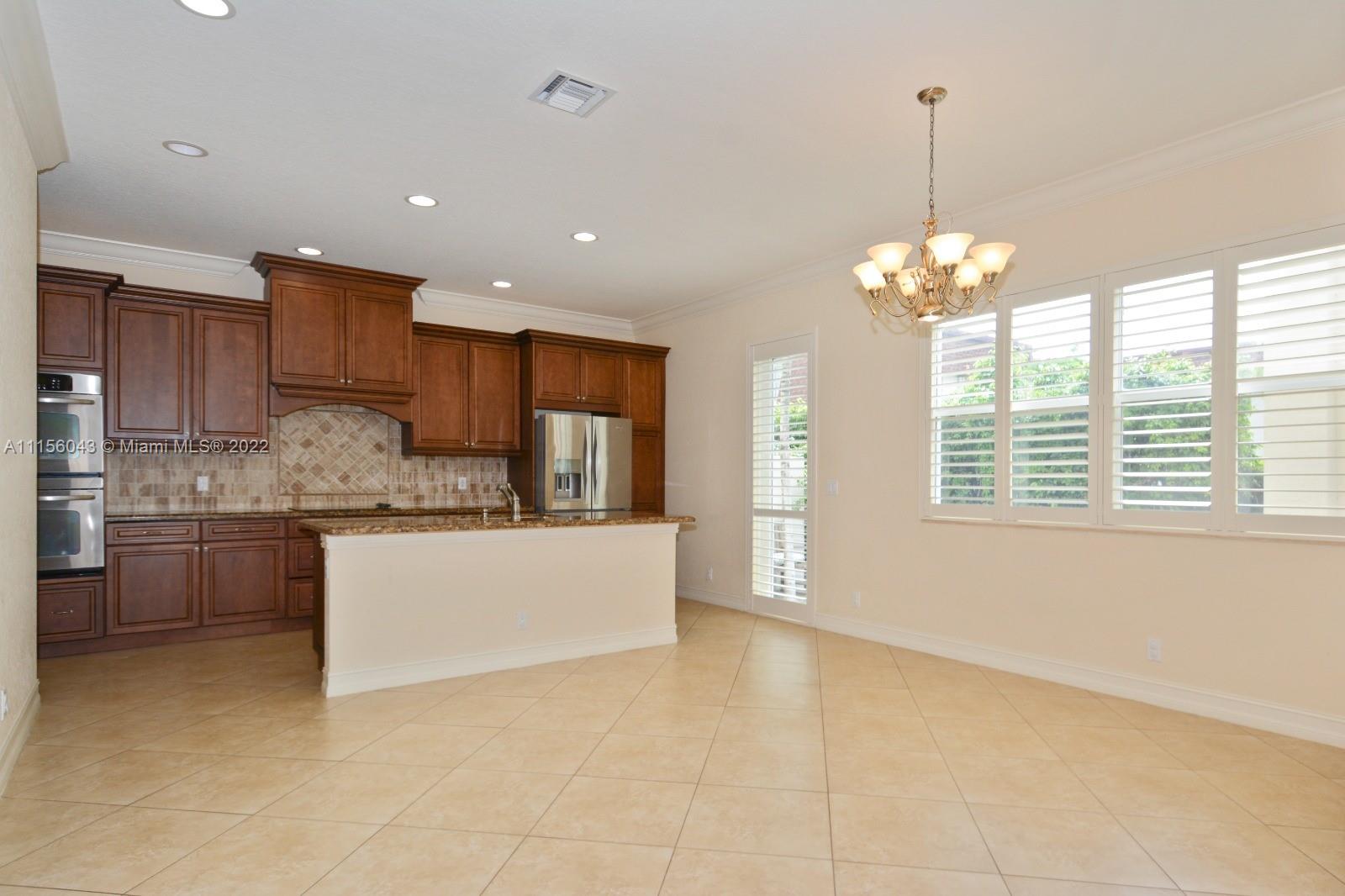 1960 Northeast 33rd Street Lighthouse Point, FL 33064 - Photo 8 of 24 a large kitchen with kitchen island white cabinets and chandelier