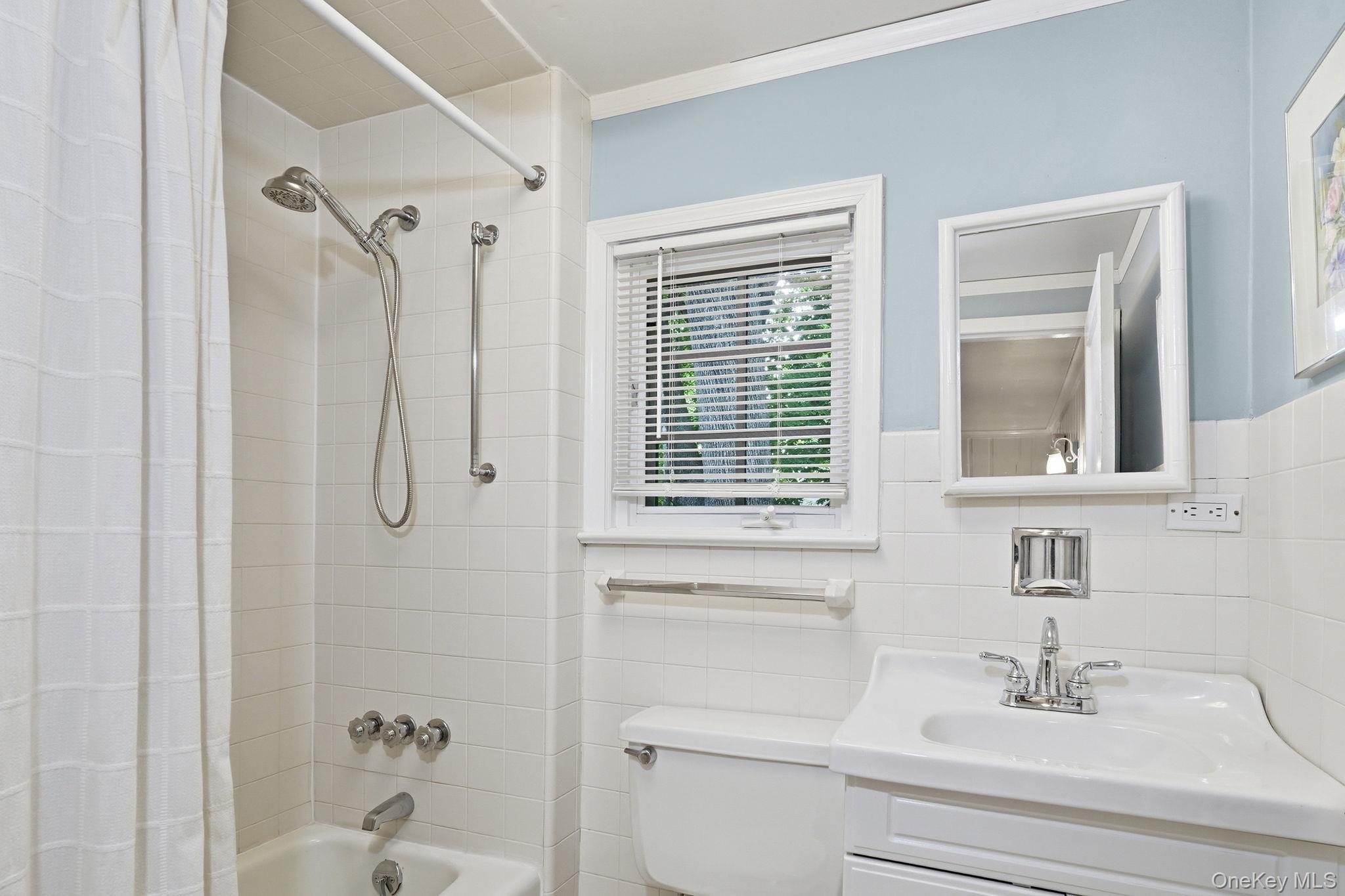 26 Cedarlawn Road Irvington, NY 10533 - Photo 19 of 34 a bathroom with a sink a mirror a window and a shower