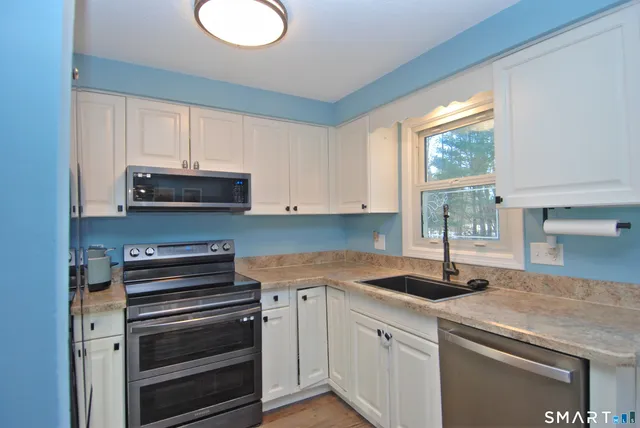 a kitchen with granite countertop a sink stainless steel appliances and cabinets