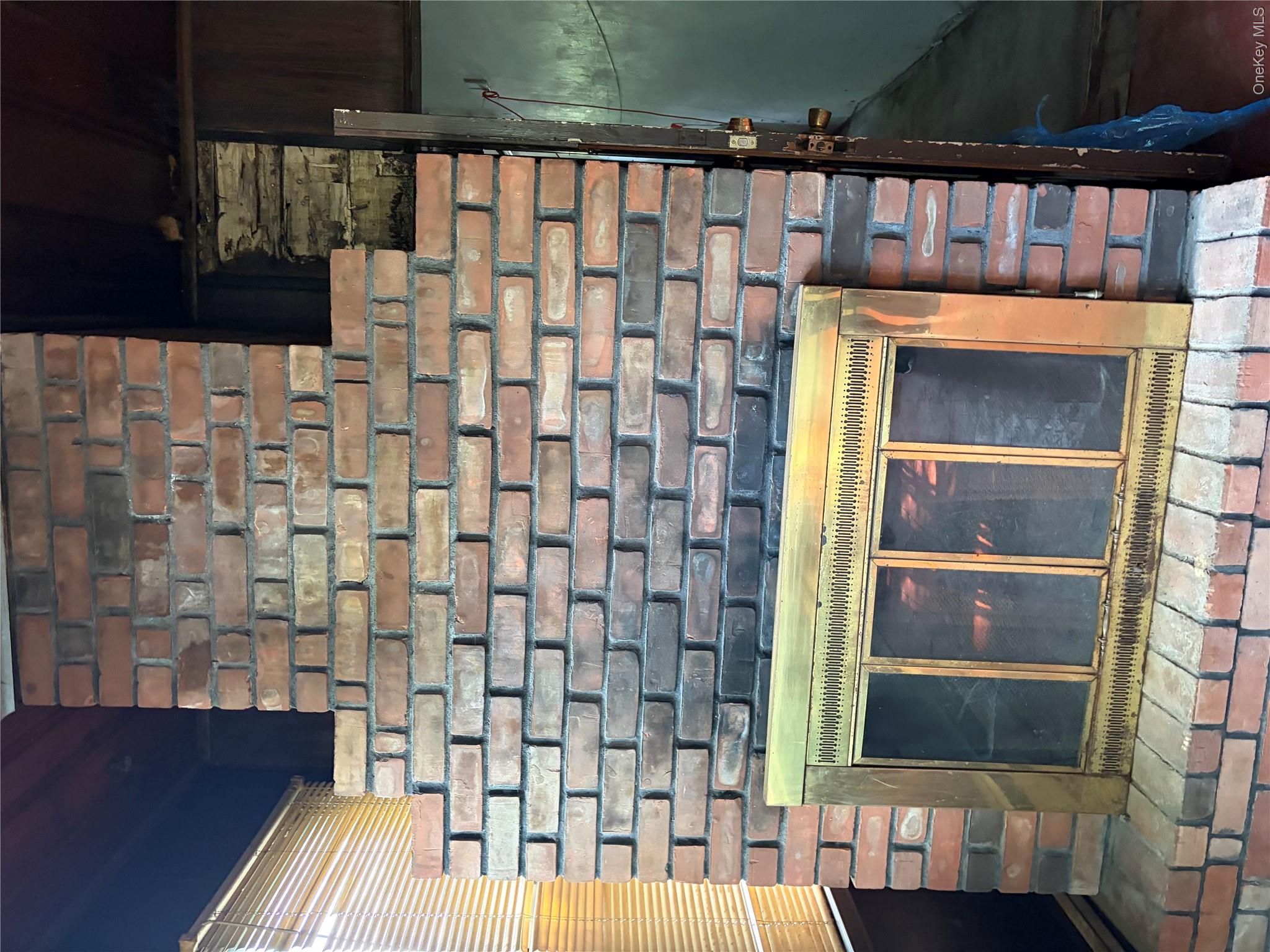 182 East Rockaway Road Hewlett, NY 11557 - Photo 5 of 8 Brick fireplace featuring a brass-tone firebox surround and a raised brick hearth