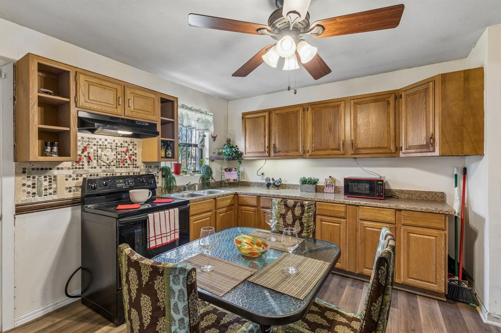 2622 Centerville Road Dallas, TX 75228 - Photo 6 of 22 a kitchen with stainless steel appliances granite countertop a stove top oven a sink a dining table and chairs with wooden floor