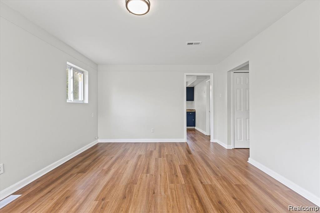 3930 Bayhan Street Inkster, MI 48141 - Photo 3 of 14 Spacious room featuring wood-finish flooring, light grey walls, white baseboards, and a flush-mount ceiling light