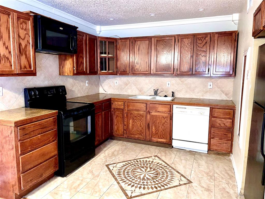 a kitchen with stainless steel appliances granite countertop wooden cabinets a stove top oven with a sink and dishwasher