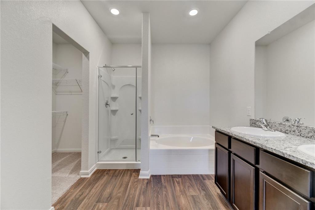 105 Brunswick Lane Jarrell, TX 76537 - Photo 10 of 16 Bathroom with dark wood-type flooring, double vanity, a shower stall, a spacious closet, and recessed lighting