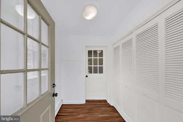 a view of a hallway with wooden floor and a bathroom