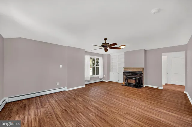 a view of empty room with wooden floor and fireplace