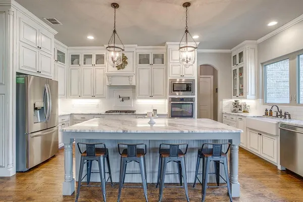a kitchen with stainless steel appliances granite countertop a kitchen island hardwood floor and a sink