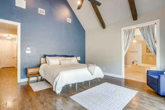 a bedroom with a bed a mirror on dresser and a wooden floor