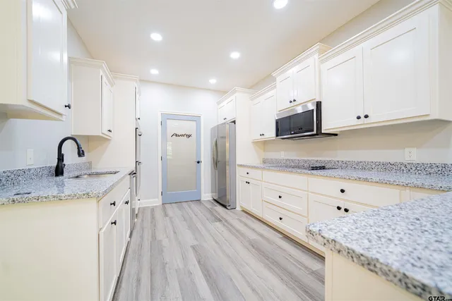 a kitchen with granite countertop white cabinets and sink