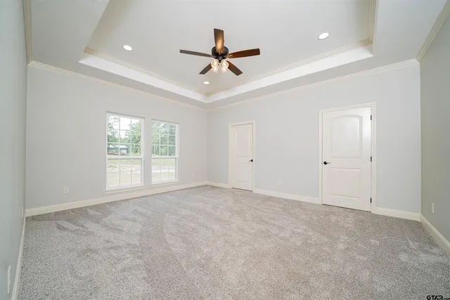 an empty room with ceiling fan and windows