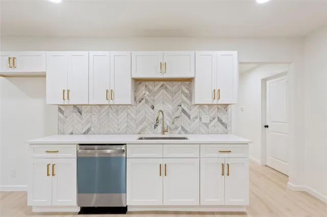 a kitchen with white cabinets and sink