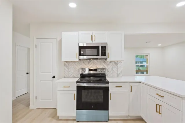 a kitchen with white cabinets and black appliances