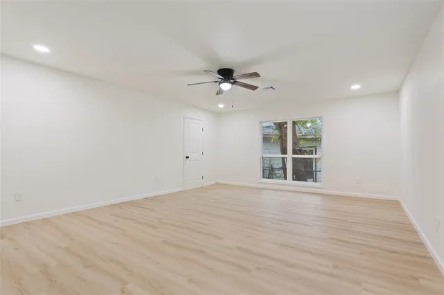 a view of an empty room with a window and wooden floor