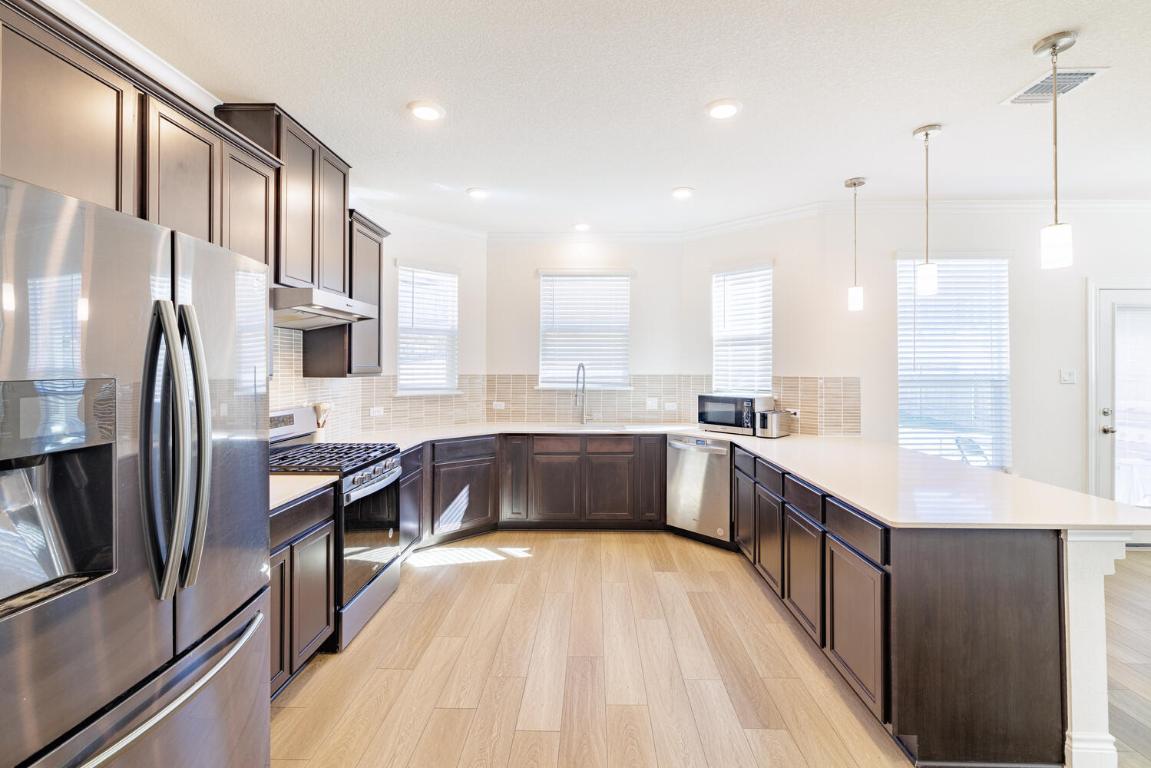 4641 Alfano Loop Round Rock, TX 78665 - Photo 11 of 32 a large kitchen with a large window and stainless steel appliances