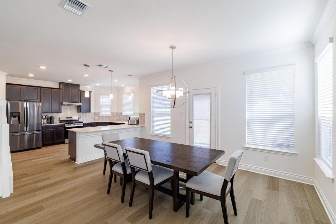 4641 Alfano Loop Round Rock, TX 78665 - Photo 12 of 32 a kitchen with a dining table chairs wooden floor cabinets and appliances