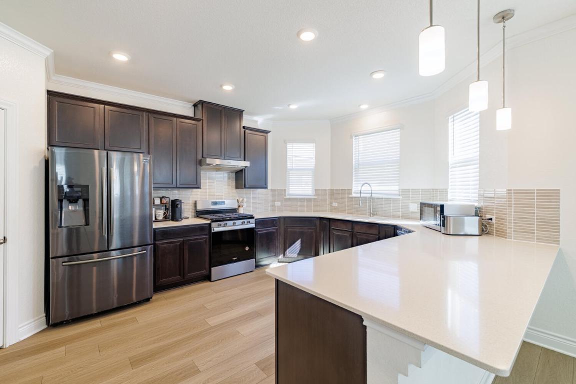 4641 Alfano Loop Round Rock, TX 78665 - Photo 8 of 32 a kitchen with stainless steel appliances kitchen island granite countertop a refrigerator a sink dishwasher a stove and a refrigerator with wooden floor