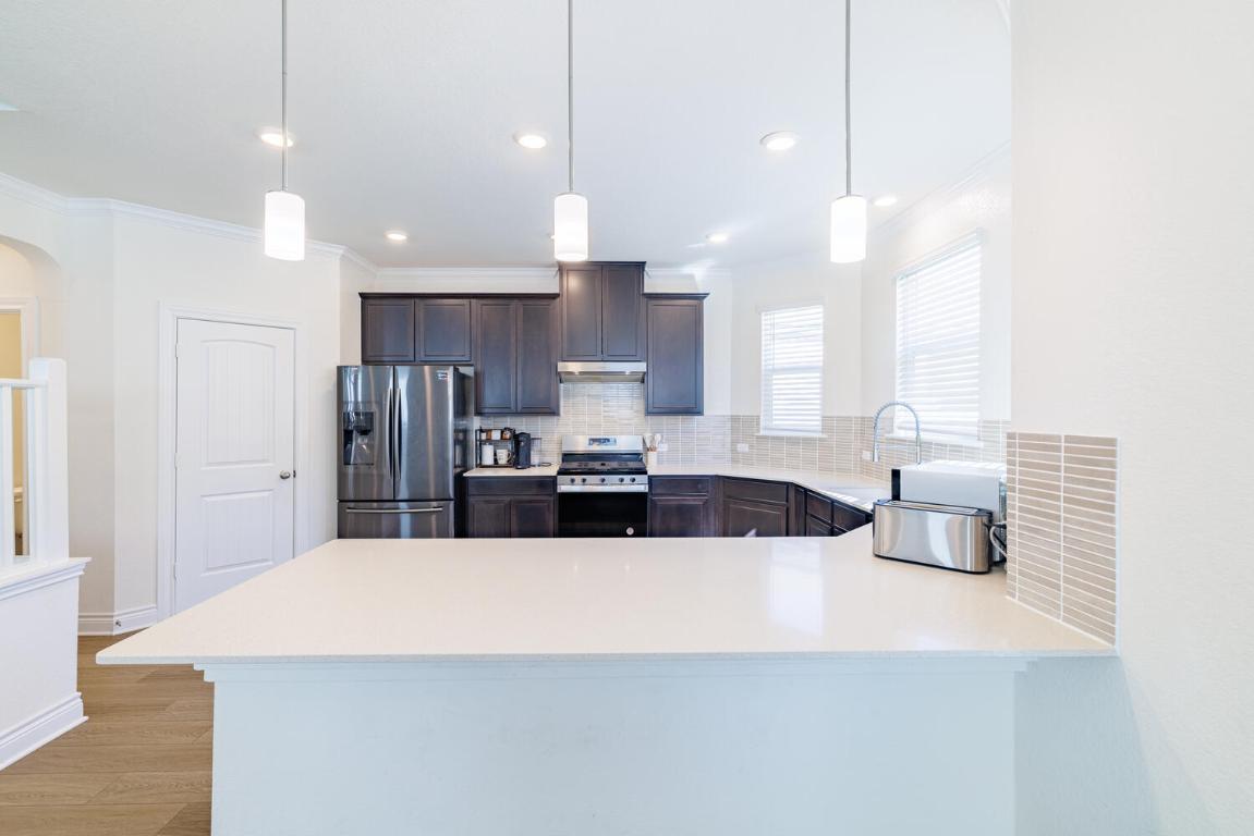 4641 Alfano Loop Round Rock, TX 78665 - Photo 10 of 32 a kitchen with kitchen island a refrigerator a sink and a stove