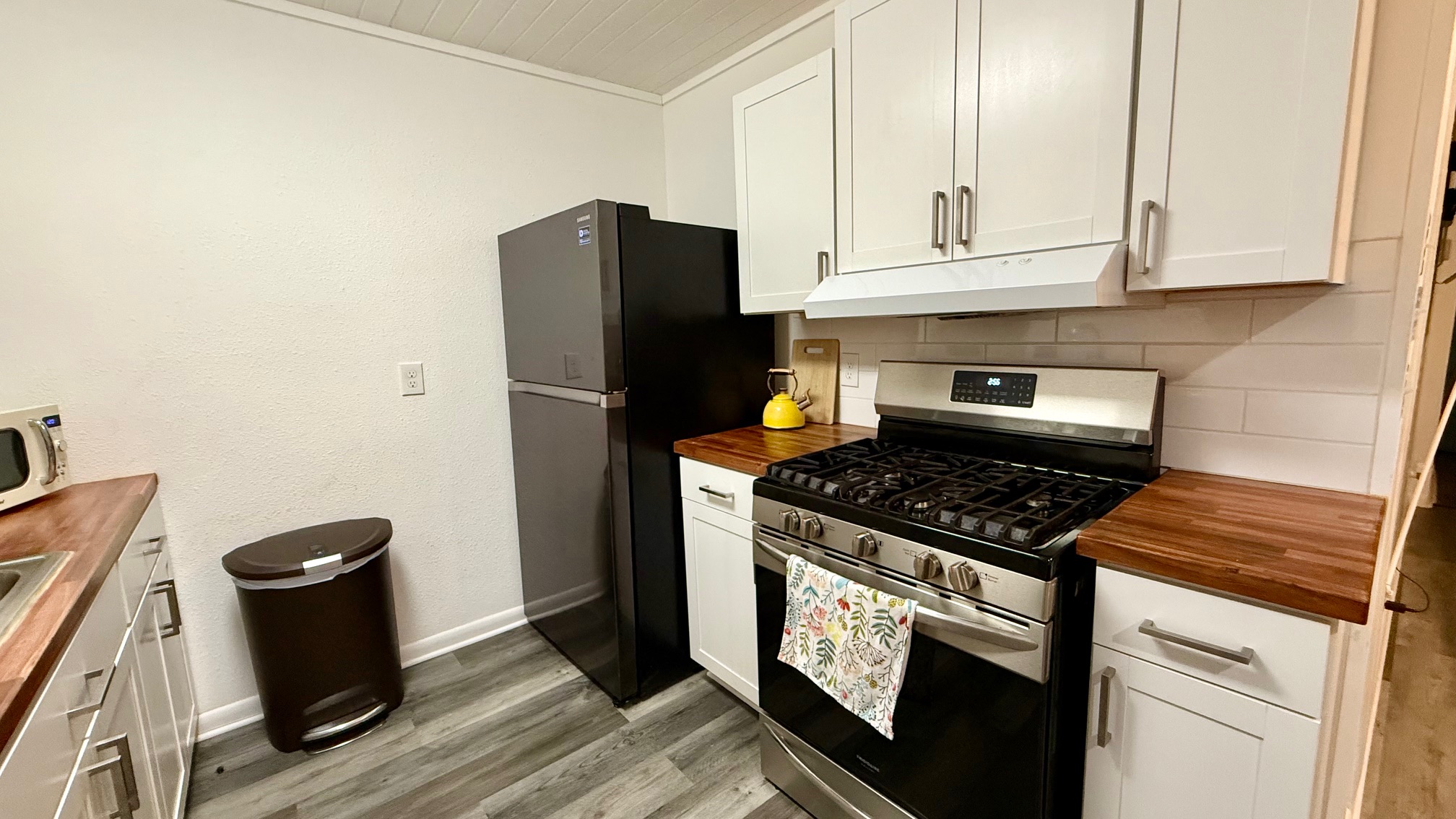 1802 East University Avenue, Unit A Georgetown, TX 78626 - Photo 21 of 23 Kitchen featuring stainless steel gas stove, wood counters, white cabinetry, under cabinet range hood, and ornamental molding