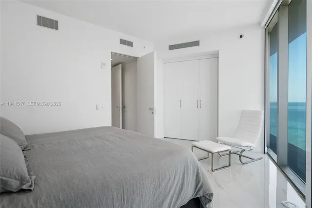 a bedroom with a large window and a balcony