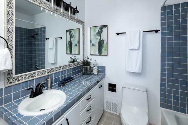 a bathroom with a granite countertop double vanity sink a mirror and a toilet