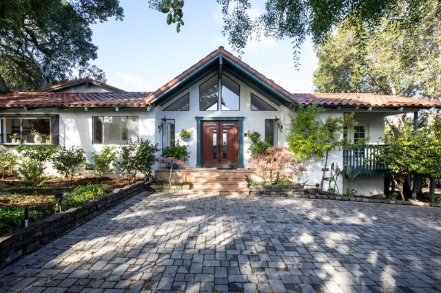 a front view of a house with a yard and potted plants