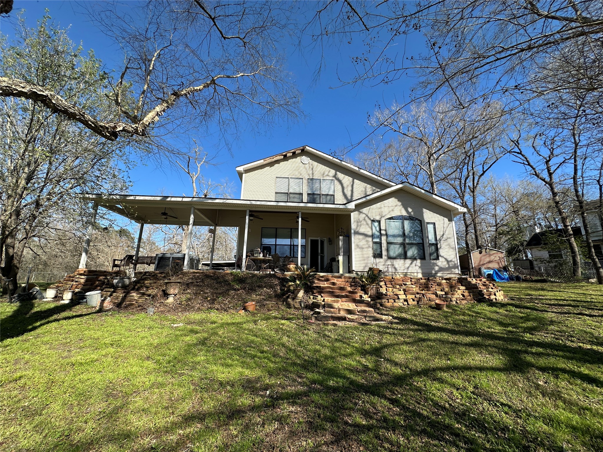 35 Susan Drive Cleveland, TX 77327 - Photo 31 of 33 Charming two-story home with a spacious covered patio, set on a sloped grassy yard. Surrounded by mature trees, it offers a serene, natural setting perfect for relaxation and outdoor activities.