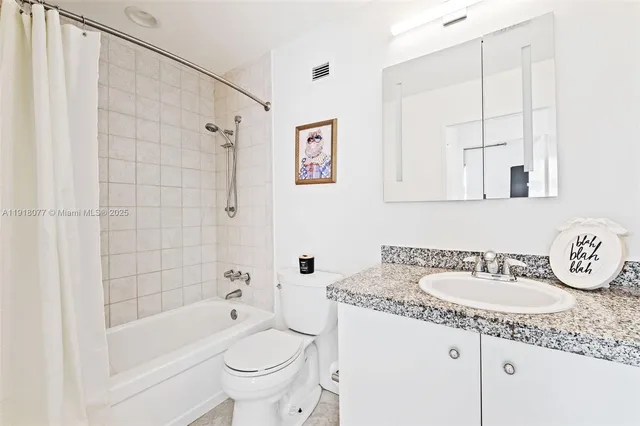 a bathroom with a granite countertop sink a toilet and bathtub