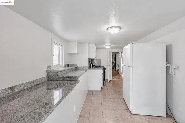 a large white kitchen with a refrigerator a stove and a window