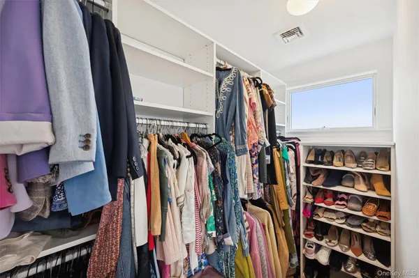 a view of walk in closet with clothes and shoes