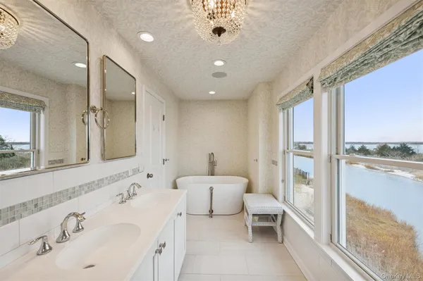 a spacious bathroom with a double vanity sink a large mirror and a bathtub