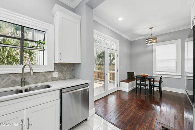 a kitchen with stainless steel appliances granite countertop a stove top oven a sink a dining table and chairs with wooden floor