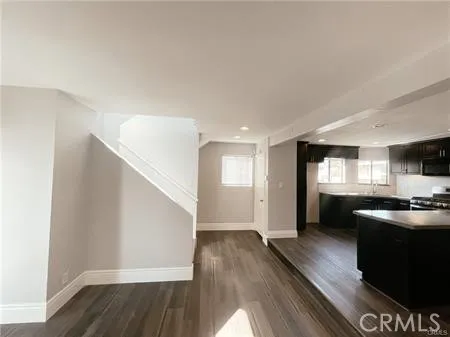 a living room with stainless steel appliances kitchen island granite countertop a stove a sink and a refrigerator