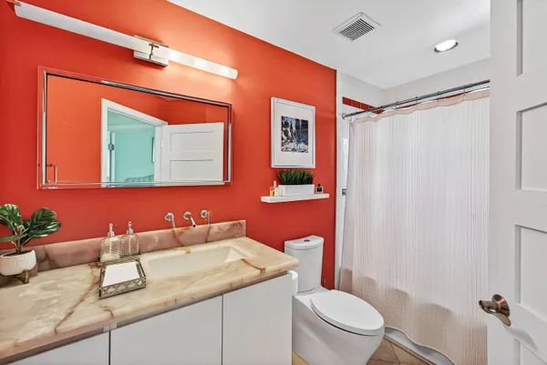 a bathroom with a granite countertop sink mirror vanity and toilet