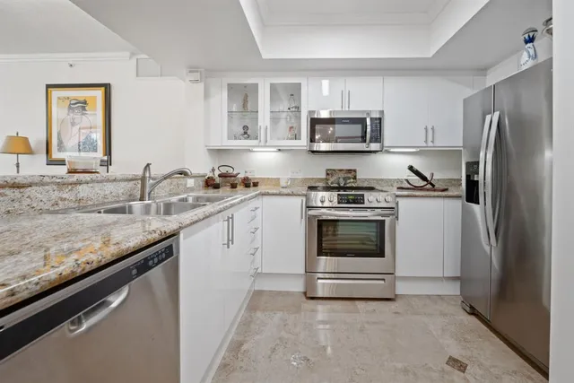 a kitchen with granite countertop white cabinets and stainless steel appliances