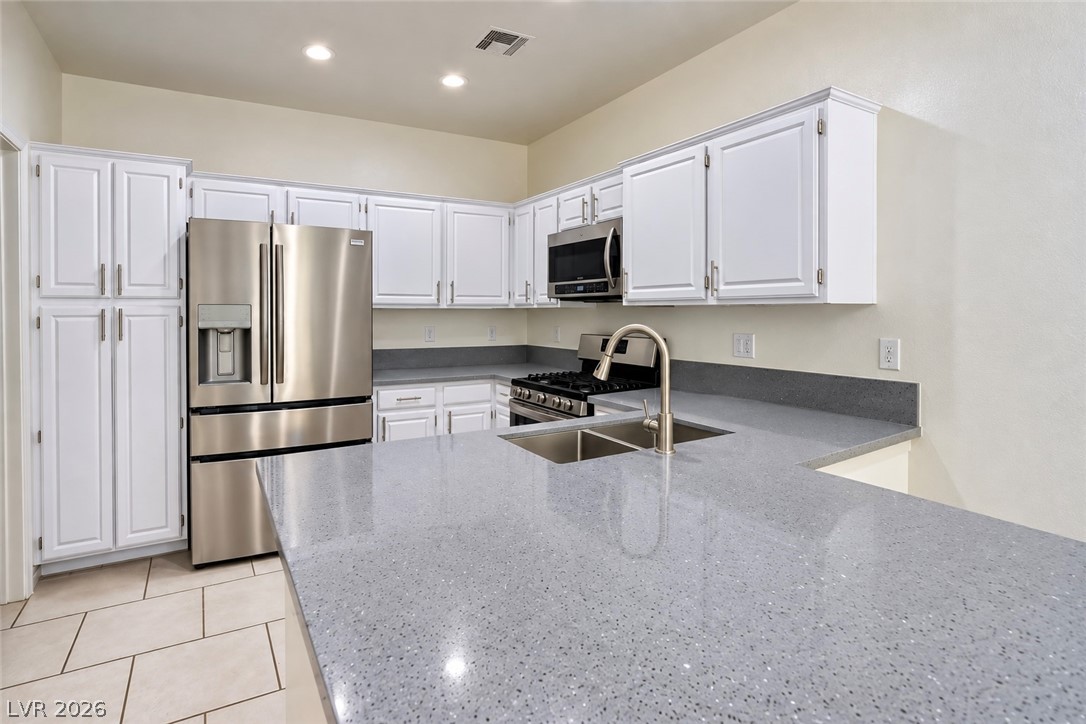 3104 Maple Ridge Court Henderson, NV 89052 - Photo 9 of 25 Polished stone counters pair beautifully with clean white cabinetry and classic tile floors.