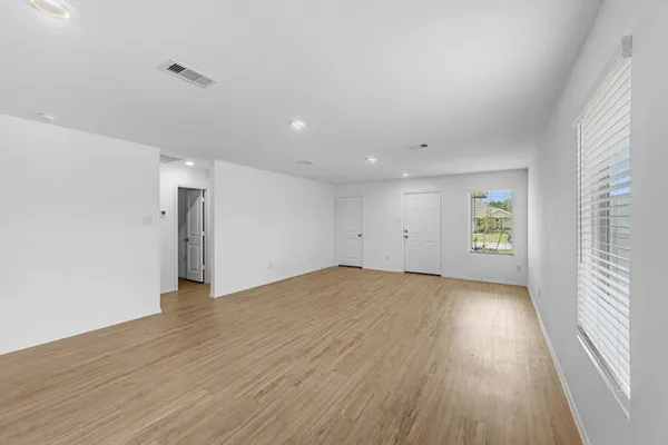 an empty room with wooden floor and windows