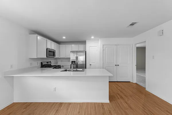 a kitchen with stainless steel appliances a sink a stove a refrigerator cabinets and a counter space